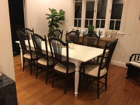 White wooden dining table and 8 black wooden chairs