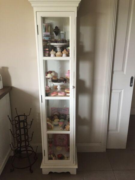 Provincial home living cabinet filled with decorative cakes