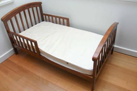 Timber child cot with guardrails along with a mattress